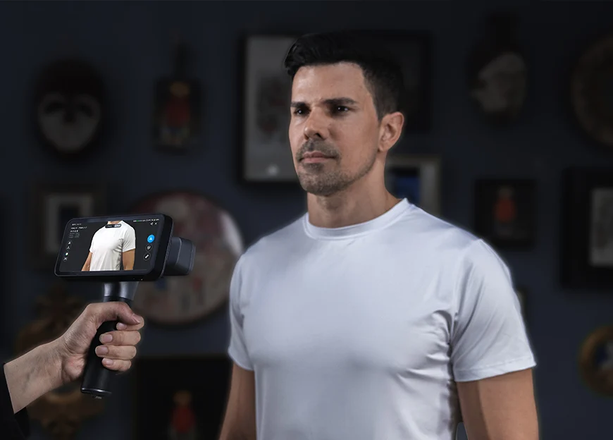 A person holding an EinScan Rigil scanner while digitising the upper body of a man standing still for an infrared scan.