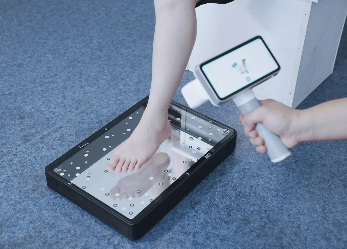 The EinScan Medixa captures foot geometry while the patient stands on the FootStation 2 accessory for combined surface and plantar scanning.