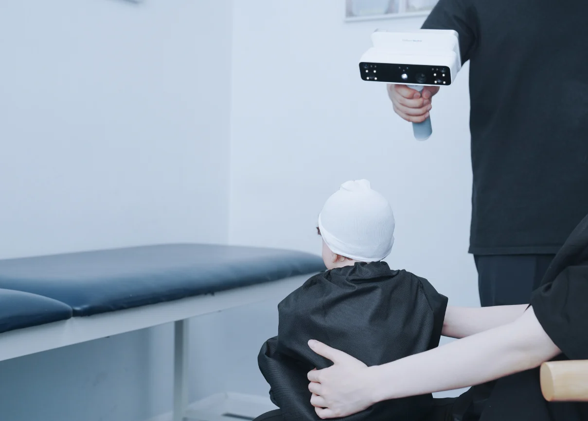 A clinician scans the head of a seated infant using the EinScan Medixa, capturing cranial data without physical contact.