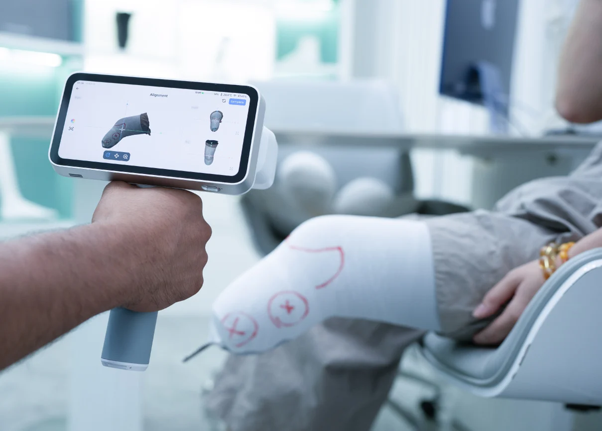 A clinician scans a patient’s lower leg and foot wrapped in marked plaster using the EinScan Medixa.