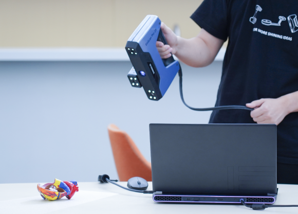 User scanning a small, detailed model with the EinScan Pro 2X V2 handheld 3D scanner.