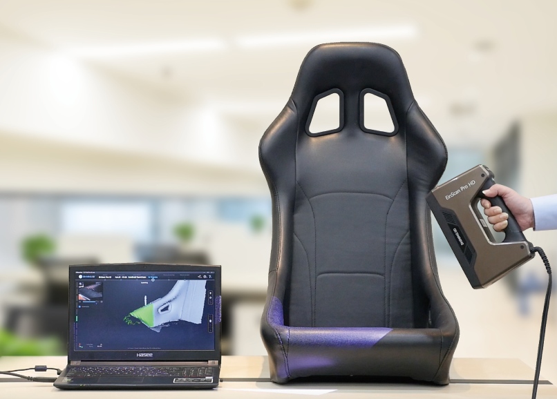 Scanning a car racing seat with the EinScan Pro HD, with real-time 3D data displayed on a laptop.