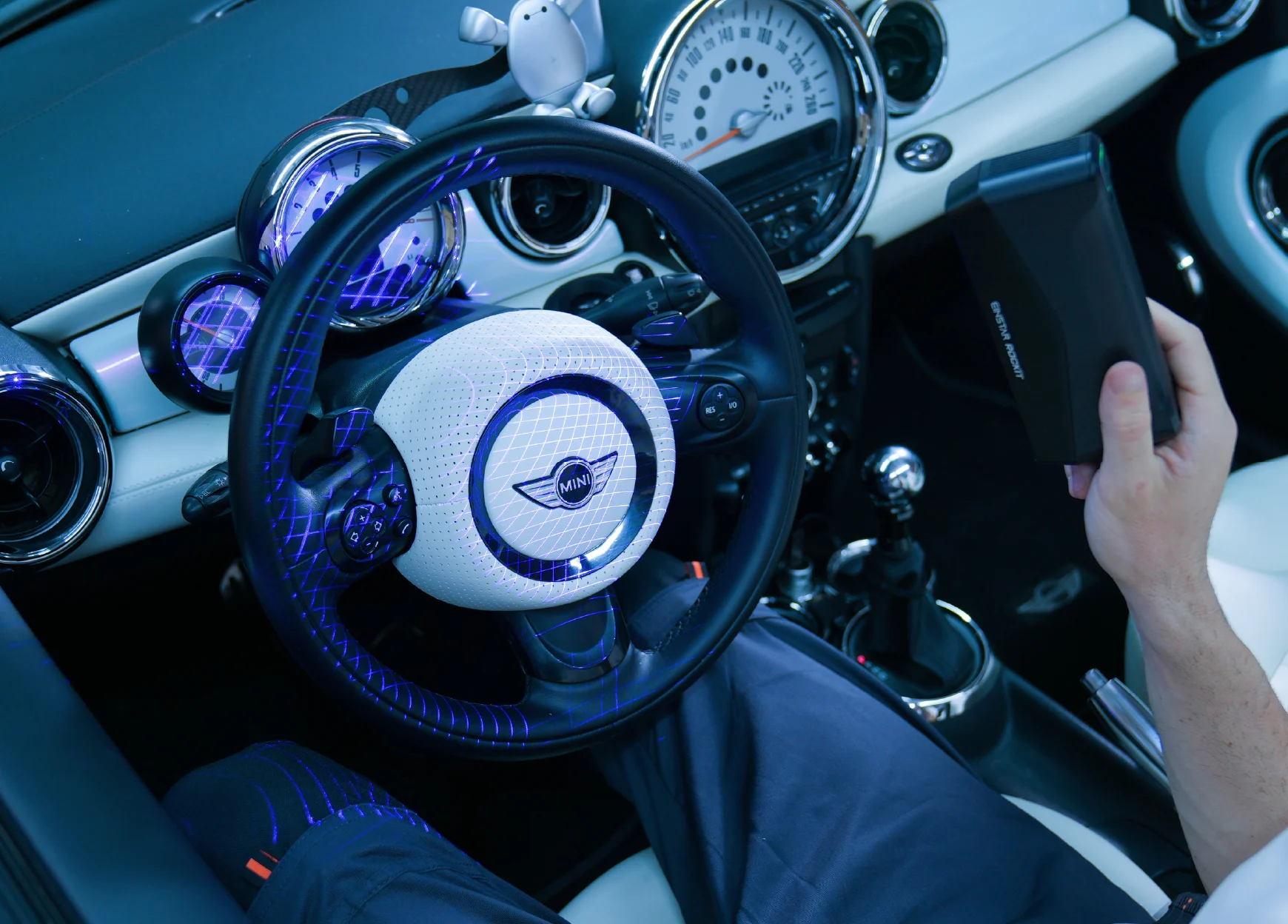 EINSTAR Rockit used wirelessly to scan a steering wheel and dashboard interior, displaying blue laser projection patterns.