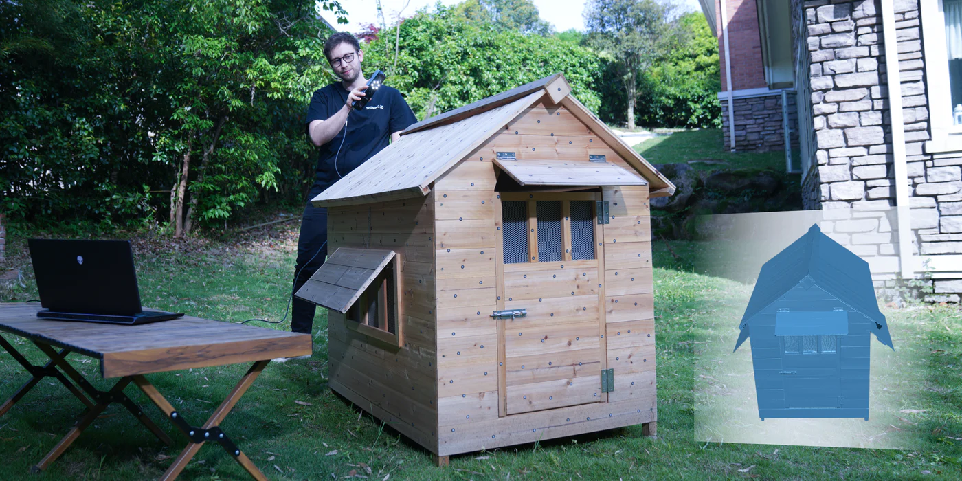 A person scanning a wooden playhouse outdoors with the Einstar, with a 3D model preview shown beside it.