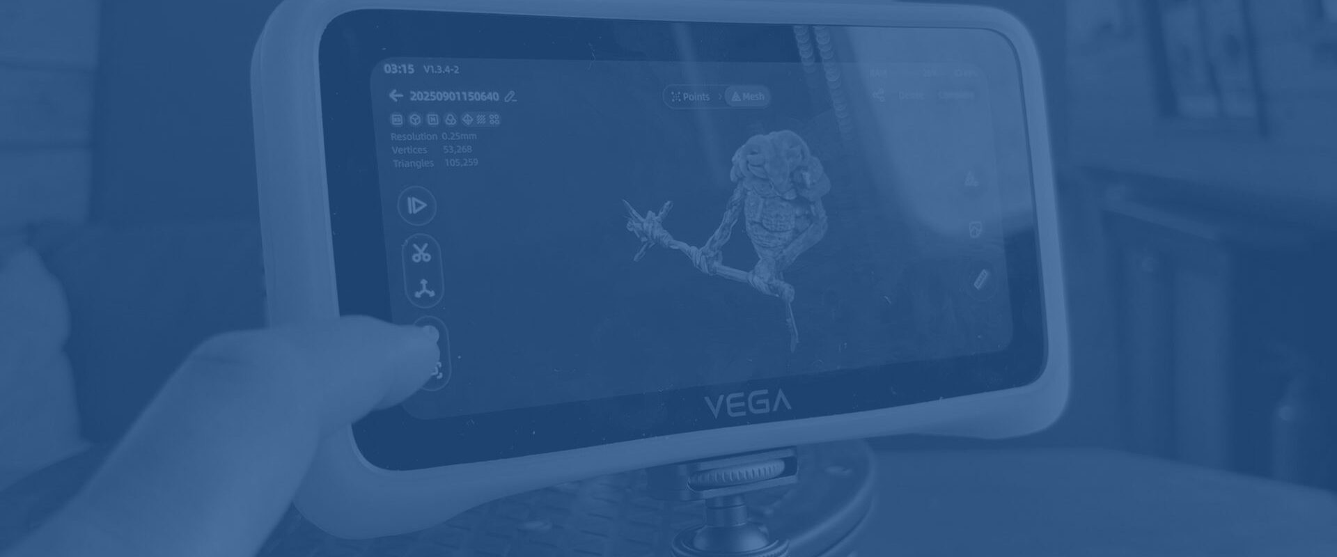 The EINSTAR VEGA 3D scanner mounted on a tripod, showing a scan of a small fantasy miniature on its display while a user interacts with the touchscreen.