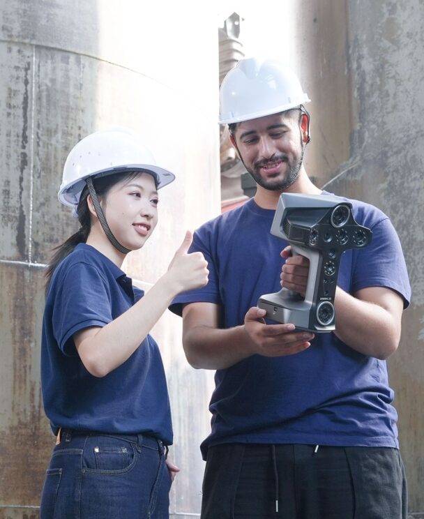 Engineers reviewing scan data while holding a Shining 3D EinScan handheld 3D scanner on an industrial site.